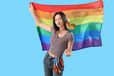 Mavi arka planda gökkuşağı bayrağı ve kalbi olan güzel genç bir kadın. LGBT kavramı