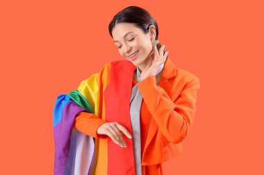 Turuncu arka planda gökkuşağı bayrağı olan güzel genç bir kadın. LGBT kavramı