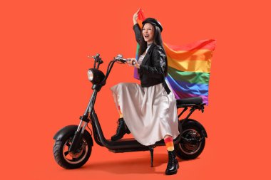 Gökkuşağı çorapları ve turuncu arka planda bayrak üstünde bisikleti olan güzel genç bir kadın. LGBT kavramı