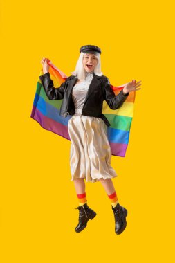 Sarı arka planda gökkuşağı bayrağıyla atlayan güzel genç bir kadın. LGBT kavramı