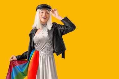 Sarı arka planda gökkuşağı bayrağı olan güzel genç bir kadın. LGBT kavramı