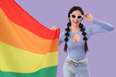 Leylak arka planında gökkuşağı bayrağı olan güzel genç bir kadın. LGBT kavramı