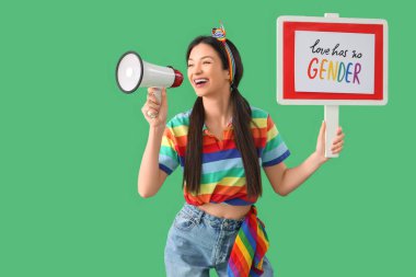 Gökkuşağı tişörtlü, elinde hoparlör olan güzel bir kadın ve yeşil arka planda 