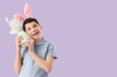 Tavşan kulaklı ergen çocuk. Leylak arka planında Paskalya hediyesi yumurtası.