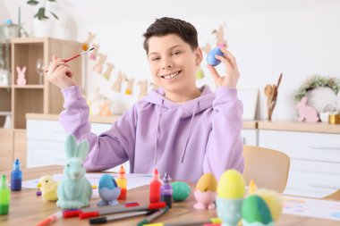 Ergen çocuk mutfakta paskalya yumurtası boyuyor.