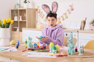 Tavşan kulaklı genç bir çocuk mutfakta paskalya yumurtalarını boyadı.