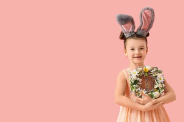 Pembe arka planda Paskalya çelengi olan tavşan kulaklı şirin bir kız.