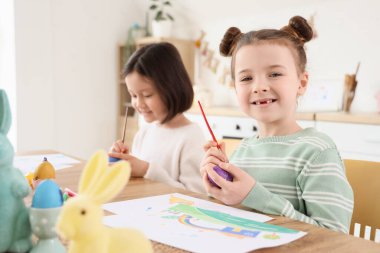 Küçük tatlı kızlar mutfakta paskalya yumurtası boyuyor.