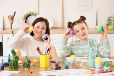 Mutfaktaki masada boyalı Paskalya yumurtaları olan sevimli küçük kızlar.