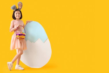 Sarı arka planda Paskalya yumurtaları olan tavşan kulaklı tatlı Asyalı kız.