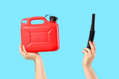 Erkek eller mavi arka planda teneke kutu ve lastik başlık tutuyor.