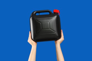 Erkek eller mavi arka planda teneke kutu tutuyor.