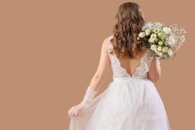 Bej arka planda çiçekli beyaz gelinlik içinde güzel bir gelin.