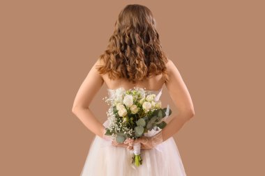 Bej arka planda çiçekli beyaz gelinlik içinde güzel bir gelin.