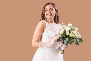 Bej arkaplanda çiçekler olan beyaz gelinlik içinde güzel bir gelin.