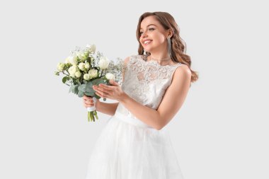 Beyaz gelinlik içinde, açık arkaplanda çiçekler olan güzel bir gelin.