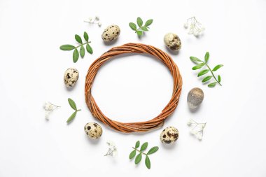 Beyaz arka planda çelenk, Paskalya yumurtası, çiçek ve yeşil yapraklardan yapılmış çerçeve