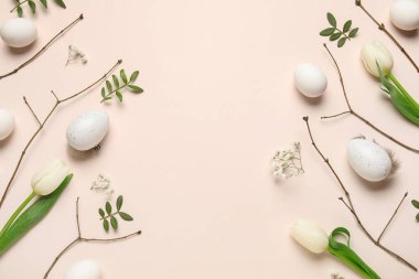 Paskalya yumurtalarından, dallardan, çiçeklerden ve bej arkaplanda yeşil yapraklardan yapılmış çerçeve