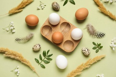 Yumurta tutacağı, Paskalya yumurtası, yeşil yapraklar ve yeşil arka planda tüyleri olan kompozisyon