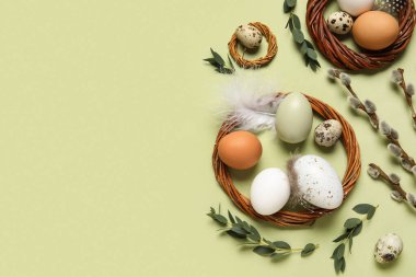 Composition with wreaths, Easter eggs, pussy willow branches and feathers on green background