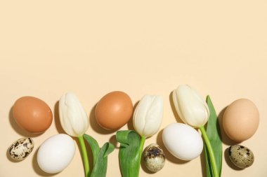 Bej arka planda Paskalya yumurtaları ve lale çiçekleri