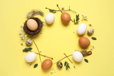 Paskalya yumurtalarından, çiçeklerden, dallardan ve sarı arkaplanda yapraklardan yapılmış çerçeve