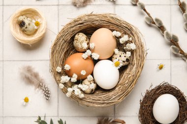 Paskalya yumurtaları, çiçekler, tüyler ve söğüt dalları beyaz fayanslı arka planda, yakın plan