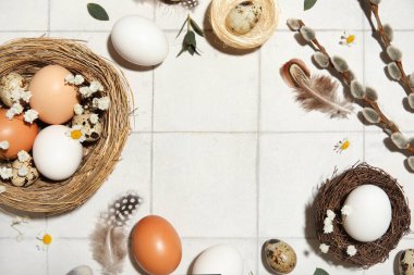 Yuvadan, Paskalya yumurtalarından, çiçeklerden ve beyaz fayanslı arkaplanda söğüt dallarından yapılmış çerçeve