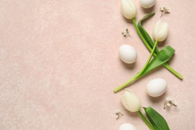 Paskalya yumurtaları ve pembe arkaplanda lale çiçekleri.