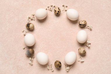 Paskalya yumurtalarından ve pembe arkaplanda çiçeklerden yapılmış çerçeve