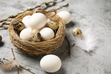 Paskalya yumurtaları, tüyleri ve söğüt dalları olan gri grunge arka planda, yakın plan
