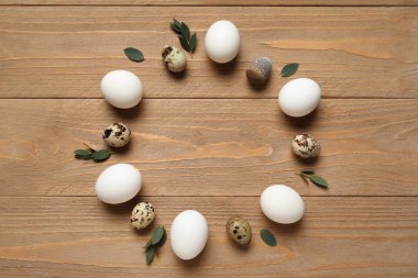 Paskalya yumurtalarından ve ahşap arka plandaki yapraklardan yapılmış.