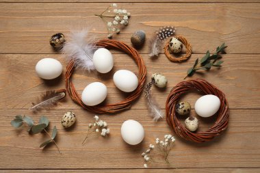 Tahta arka planda çelenkli, çiçekli ve tüylü Paskalya yumurtaları