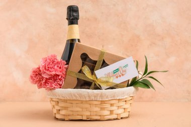 Bej rengi grunge arka planda Anneler Günü için karanfilli sepet, şampanya şişesi ve çikolata şekeri.