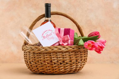 İçinde şarap şişesi, lale ve hediye kutusu olan sepet. Bej rengi grunge arka planda Anneler Günü için.