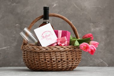 Şarap şişesi, lale ve Anneler Günü için hediye paketi masadaki gri grunge arka planda.