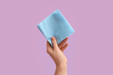 Leylak arka planında mavi kağıt peçeteli bir kadın.