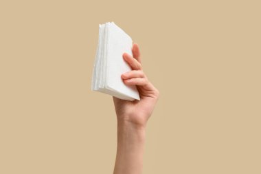 Bej arka planda kağıt peçeteli bir kadın.