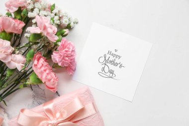 Tebrik kartı ve beyaz arka planda hediye kutusu olan farklı güzel çiçeklerden oluşan bir buket. Anneler Günü kutlaması