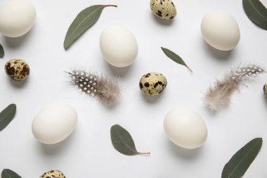 Gri arka planda yaprakları olan tavuk ve bıldırcın yumurtaları. Paskalya kutlaması