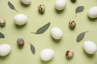 Yeşil arka planda yaprakları olan tavuk ve bıldırcın yumurtaları. Paskalya kutlaması