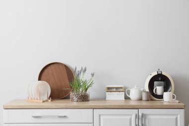 Kahve makineli güzel Muscari çiçekleri ve mutfak tezgahlarında ışık duvarının yanında tabaklar.