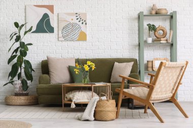 Oturma odasının içinde kanepe, koltuk, nergis çiçekleri ve kahve masasında dergiler var.