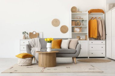 Oturma odasının içinde kanepe, gardırop, güzel lale çiçekleri ve kahve masasında dergiler var.