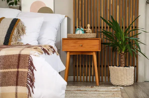 Hasır tepsi, çalar saat ve biblo yatak odasındaki komodinin yanında.