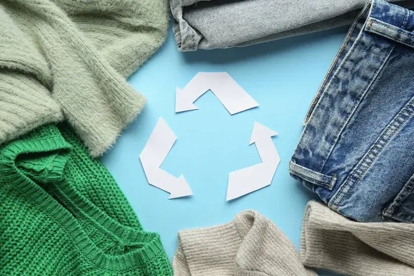 Mavi arkaplanda geri dönüşüm logosu olan kıyafetler
