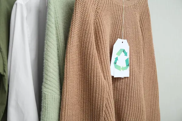 Beyaz arkaplanda asılı geri dönüşüm etiketli giysiler, yakın plan