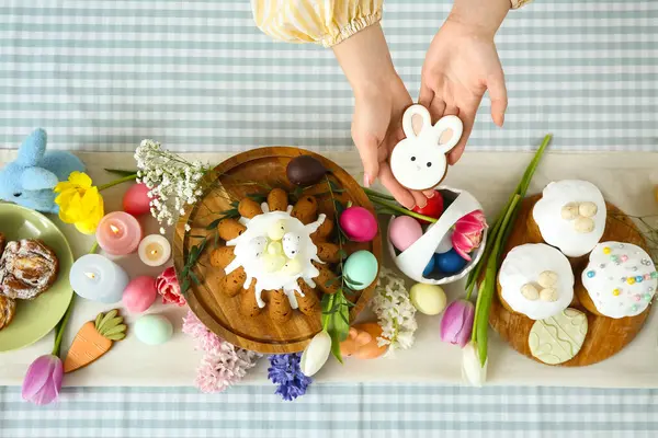 Paskalya kutlaması için masa başında zencefilli çörek şeklinde zencefilli ekmek tutan kadın eller. Üst görünüm