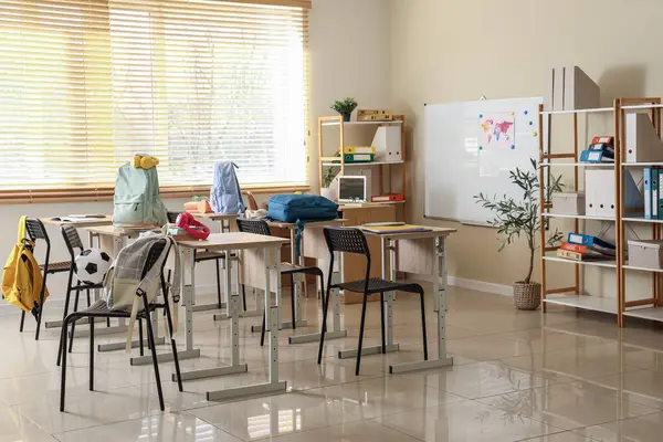 Raflar, masalar ve sırt çantaları olan sınıfın içi