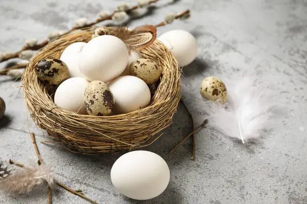 Paskalya yumurtaları, tüyleri ve söğüt dalları olan gri grunge arka planda, yakın plan
